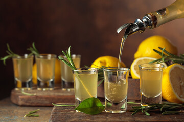 Italian liqueur Limoncello with fresh lemons and rosemary branches.