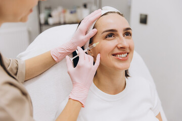 Beautician injecting botox into smiling woman's face