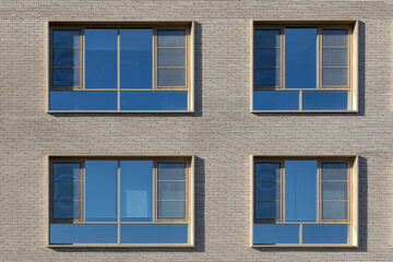 Modern facade with square windows. Exterior of a gray building with four windows, safety bars on the windows, minimal design.