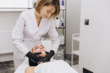 Beautician applying a face mask to a young woman lying on a massage table