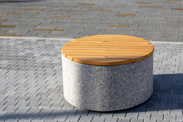 Round bench with concrete base and wooden seat on paved sidewalk. Resting place in urban...