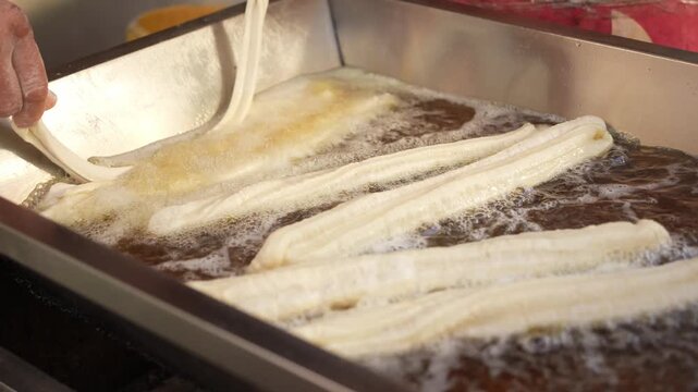 Freshly fried golden crispy youtiao being cooked in hot oil in a deep fryer