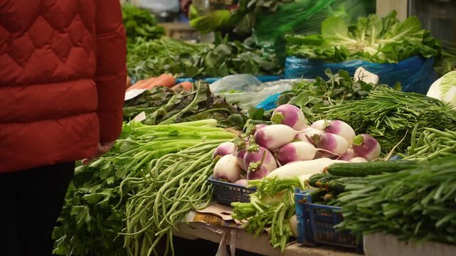 Fresh vegetables including radishes and green onions displayed on a market stall in a bustling vegetable market