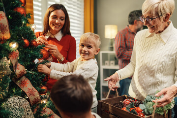 Happy family decorating christmas tree together at home