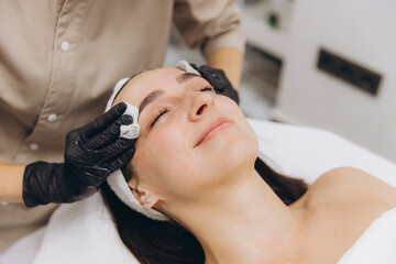 Naklejka premium Beautician Cleaning Face of Woman in Beauty Salon