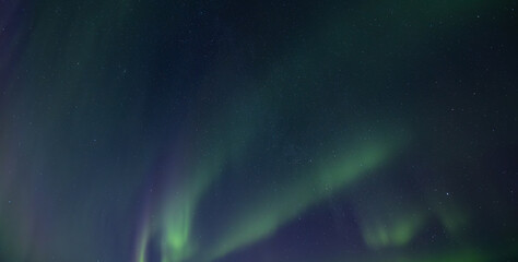 Igloo in winter forest against the backdrop of incredible starry sky with Aurora borealis. Northern lights in winter mountains. Wintry scene with glowing polar lights and icehouse. Christmas postcard