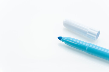 pennarello evidenziatore con punta in feltro di colore azuuro su una superfice bianca riflettenta, immagine ravvicinata