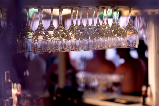 Close-up of clean wine glasses hanging in a bar - Powered by Adobe