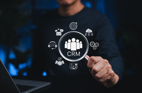 CRM Customer Relationship Management System Concept. Magnifying glass over CRM icons, symbolizing customer relationship management, data analytics, support, cloud storage, and digital marketing tools.