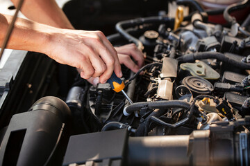 Fototapeta premium Hands repairing an engine with a screwdriver in a garage workshop during daylight