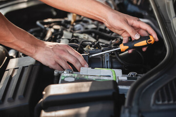 Car maintenance process at a garage with hands working on the engine using tools in the afternoon...