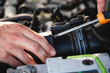Hands working on a car engine part during a routine maintenance check in a workshop setting