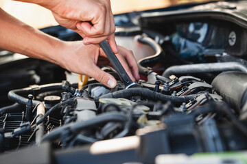 Mechanic works on car engine in outdoor setting during sunny day © Agil