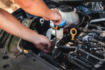Engine maintenance being performed with a tool over a vehicle in a sunny outdoor location