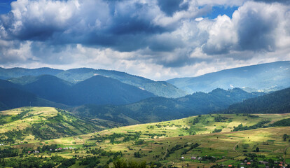 View of the Carpathian Mountains, sky with clouds and a village. Natural landscape.