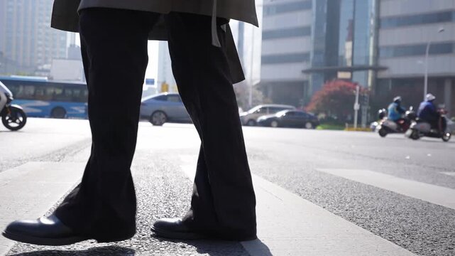 Close-up of pedestrian legs crossing a zebra crossing on a busy city street during daytime