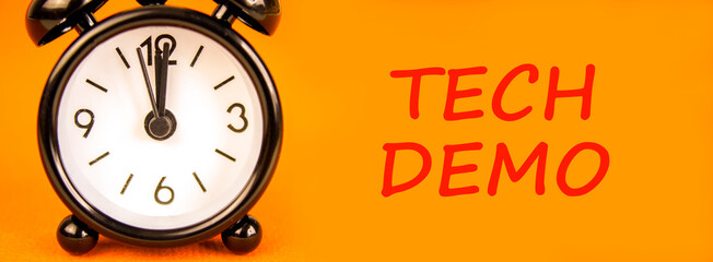 Tech demo symbol. Concept word Tech demo on beautiful orange paper. Beautiful black alarm clock....