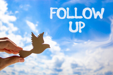 Follow up symbol. Concept word Follow up on beautiful blue sky. Businessman's hand with wooden...