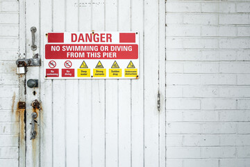 Multiple danger warning sign seen attached to a painted door at the entrance to an HM coastguard...