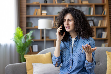 Naklejka na ściany i meble Frustrated woman arguing on phone at home