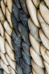 Obraz premium Detailed side view of a natural stone mosaic made of smooth, rounded black and cream pebbles. Abstract texture and pattern, ideal for backgrounds
