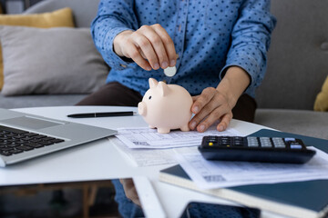 Accountant saving money in piggy bank after calculating expenses