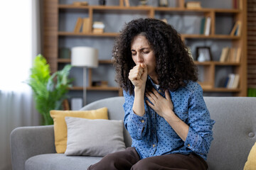 Sick woman coughing at home on sofa, suffering from cold or flu virus