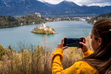 Mujer turista tomándo una foto con su celular a la isla de Bled, en Eslovenia © Javier