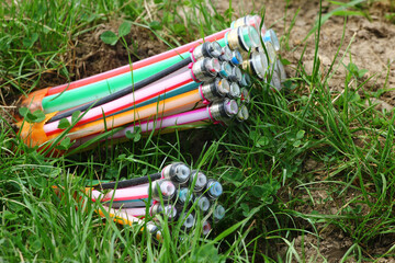 Colorful underground fiber optic cables exposed in green grass during installation or maintenance work