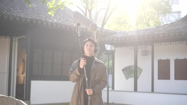 A woman holding a fan stands in a traditional Chinese courtyard with backlighting sunlight