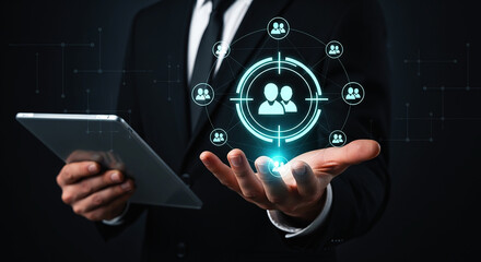 Man in suit holding tablet with glowing target and people icons hovering above his hand in dark setting on transparent background
