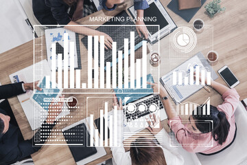 A dynamic overhead view of a marketing strategy meeting, showcasing collaboration, data analysis, and creative discussion among professionals. Impute
