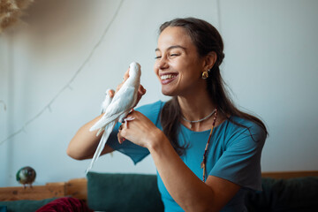Smiling woman playing with pet parrot indoors at home.  © Dexon Dee