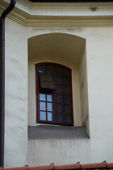 Obraz premium Arched window with wooden frames set in light facade, combining historic architectural charm with classical design elements