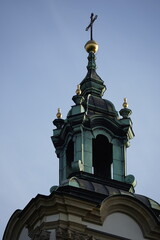 Fototapeta premium Ornate church tower with green dome and cross rises into clear sky, symbolizing heritage, spirituality, and classical architecture.