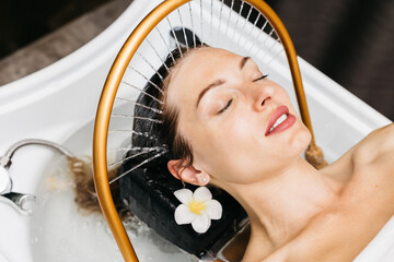 Woman enjoying hydromassage therapy in a spa setting, relaxing with water flowing gently over her...