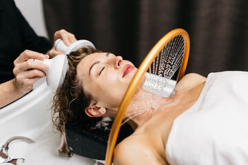 Woman enjoying hydromassage head treatment in Japanese spa, relaxing with soothing water and...