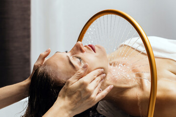 Woman receiving hydromassage therapy in a serene spa environment, water cascading gently over her...