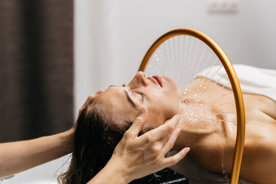 A woman receives hydromassage therapy in a tranquil spa setting. Relaxation and rejuvenation are promoted with the help of aquamassage techniques.