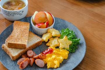 Breakfast plate with toast, scrambled eggs, sausage, fruit, and soup
