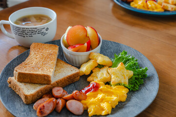 Breakfast plate with toast, scrambled eggs, sausage, fruit, and soup
