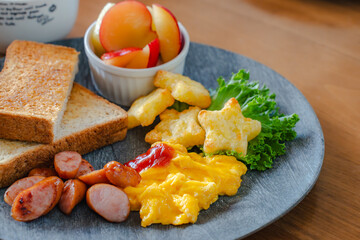 Breakfast plate with toast, scrambled eggs, sausage, fruit, and soup
