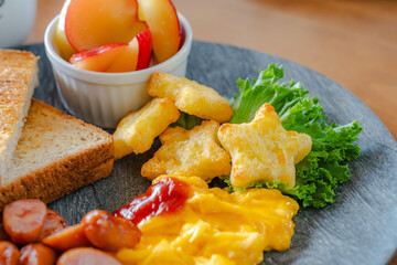 Breakfast plate with toast, scrambled eggs, sausage, fruit, and soup
