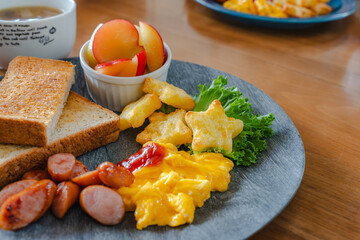Breakfast plate with toast, scrambled eggs, sausage, fruit, and soup
