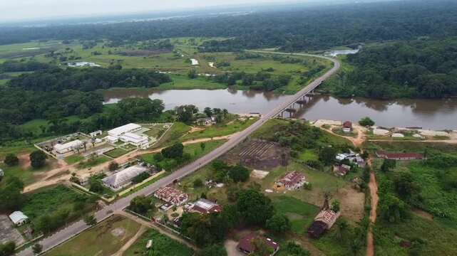Aerial View of Tropical Village with Bridge Over River and Lush Green Jungle republic of congo