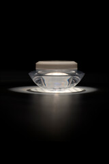 Elegant cosmetic jar with light reflection on black background
