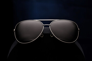 Stylish aviator sunglasses on dark background