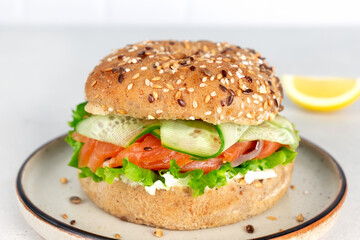 Burger or bagel with salmon, cream cheese and cucumber on a white background. Healthy breakfast.