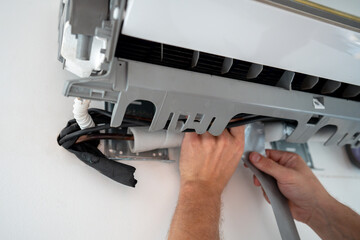 Repairman hands fix leakage of air conditioner. Worn protective covering on refrigerant line lead...