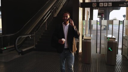 Businessman walking through subway station while talking on phone